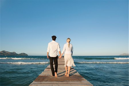 Couple walking on pier holding hands, rear view Stock Photo - Premium Royalty-Free, Code: 632-05816900