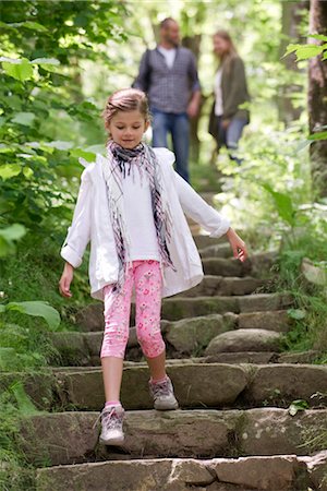 Girl walking down stone steps in woods, parents in background Stock Photo - Premium Royalty-Free, Code: 632-05845287