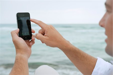 Man using smartphone at the beach Stock Photo - Premium Royalty-Free, Code: 632-05845462