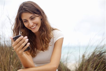 Young woman smiling at cell phone Stock Photo - Premium Royalty-Free, Code: 632-05991676