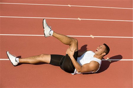 Injured runner lying on running track Stock Photo - Premium Royalty-Free, Code: 632-05991746