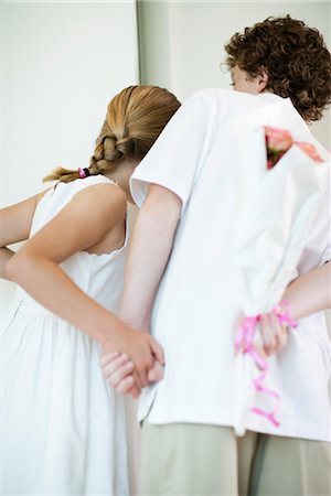 Young siblings holding bouqet of flowers behind backs, peeking through doorway Stock Photo - Premium Royalty-Free, Code: 632-05991917