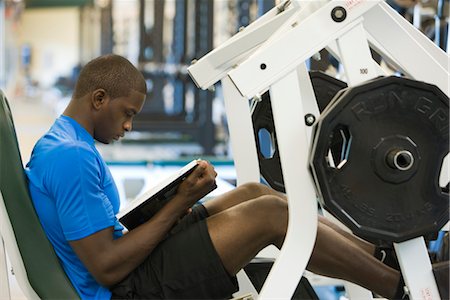 Young man reading book while lifting weights Stock Photo - Premium Royalty-Free, Code: 632-05992234