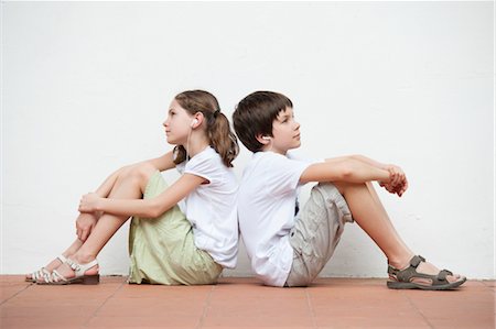 Boy and girl sitting back to back listening to music together Foto de stock - Sin royalties Premium, Código: 632-06029668