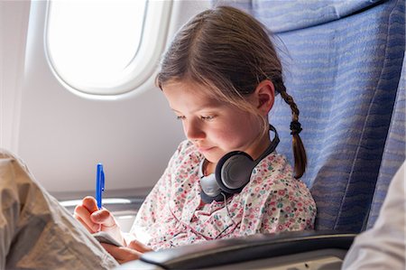 Girl writing in notebook on airplane Stock Photo - Premium Royalty-Free, Code: 632-06029684