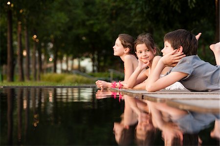 flower with reflection - Children lying together at edge of pond Stock Photo - Premium Royalty-Free, Code: 632-06029682