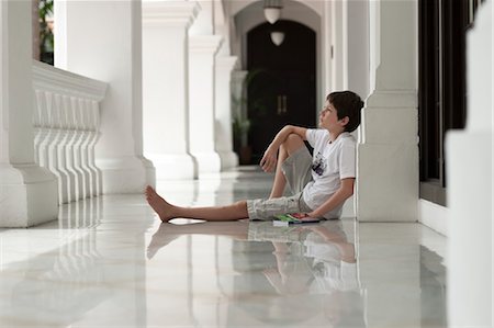 Boy sitting on floor of veranda daydreaming Foto de stock - Sin royalties Premium, Código: 632-06029718