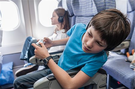 simsearch:632-06029740,k - Boy leaning out of seat on airplane to look down aisle Stock Photo - Premium Royalty-Free, Code: 632-06029765