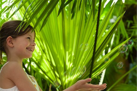 simsearch:632-05604245,k - Girl playing with bubbles under palm leaves Stock Photo - Premium Royalty-Free, Code: 632-06029871