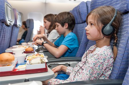 Girl watching movie on airplane, airline meal on tray table Stock Photo - Premium Royalty-Free, Code: 632-06029986