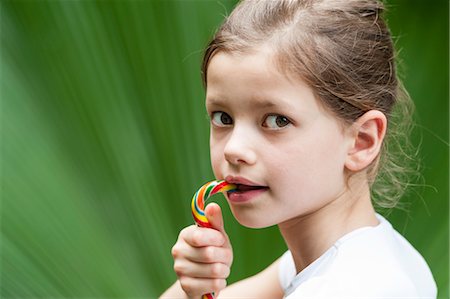 Girl eating candy, looking over shoulder Stock Photo - Premium Royalty-Free, Code: 632-06029987