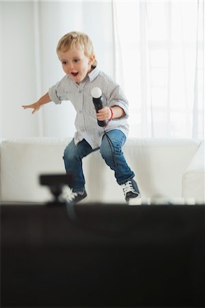Little boy jumping on sofa with microphone in hand Stock Photo - Premium Royalty-Free, Code: 632-06030019