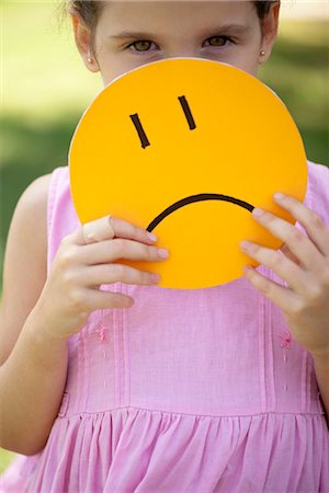 displeased - Girl hiding behind sad face mask Stock Photo - Premium Royalty-Free, Code: 632-06118183