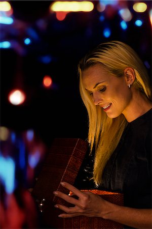 Woman illuminated by golden light as she opens Christmas gift Stock Photo - Premium Royalty-Free, Code: 632-06118245