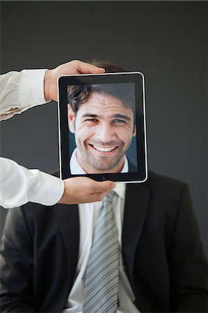 Man concealed behind digital tablet displaying image of smiling man Stock Photo - Premium Royalty-Free, Code: 632-06118317