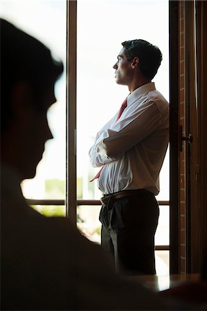 Silhouette of businessman standing by window Fotografie stock - Premium Royalty-Free, Codice: 632-06118483