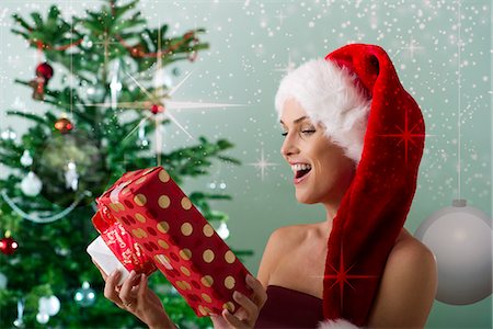 santa claus hat - Woman wearing Santa hat, looking at Christmas gifts Stock Photo - Premium Royalty-Free, Code: 632-06118616