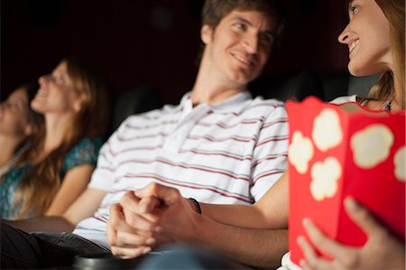 Couple looking at each other and holding hands in movie theater Stock Photo - Premium Royalty-Free, Code: 632-06118767