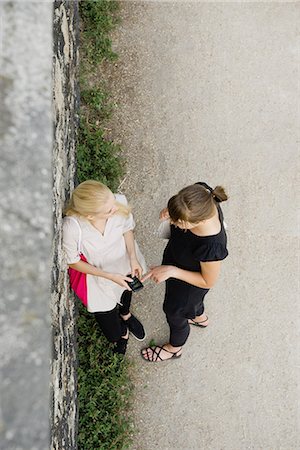 Young women looking at cell phone together outdoors, overhead view Stock Photo - Premium Royalty-Free, Code: 632-06118829