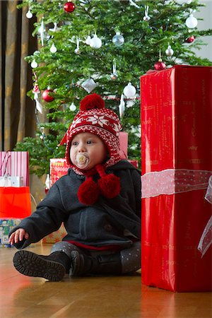 Baby girl sitting with large gift in front of Christmas tree, portrait Stock Photo - Premium Royalty-Free, Code: 632-06118913