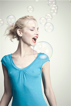Young woman surrounded by bubbles with mouth open Stock Photo - Premium Royalty-Free, Code: 632-06317864
