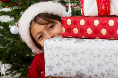 Boy peeking around stack of Christmas presents Stock Photo - Premium Royalty-Free, Code: 632-06354292
