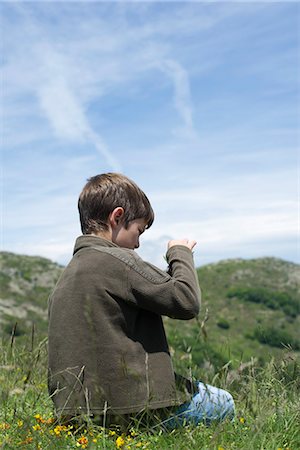 simsearch:633-05401710,k - Boy sitting on grass, looking at wildflower, rear view Stock Photo - Premium Royalty-Free, Code: 632-06404548