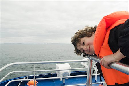 Boy leaning on the deck of a boat, smiling Stock Photo - Premium Royalty-Free, Code: 632-06779332