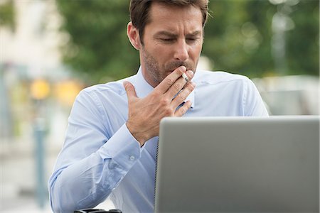 Businessman smoking while using laptop computer outdoors Foto de stock - Sin royalties Premium, Código: 632-07161463