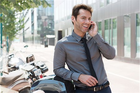 simsearch:649-07520071,k - Businessman talking on cell phone in city, leaning against motor scooters Stock Photo - Premium Royalty-Free, Code: 632-07161559