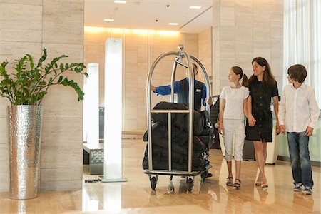 Bellhop assising mother and children with luggage in hotel lobby Stock Photo - Premium Royalty-Free, Code: 632-07161682