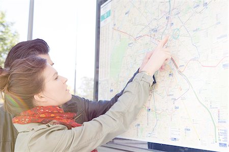 Tourist couple looking at outdoor city map at tourist information station Stock Photo - Premium Royalty-Free, Code: 632-07674498