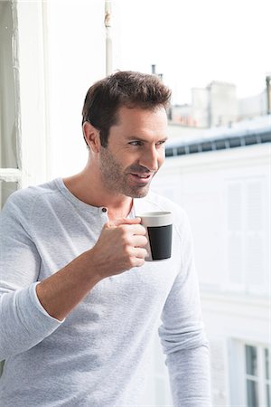 Man looking out of window with mug in hand Stock Photo - Premium Royalty-Free, Code: 632-07674625