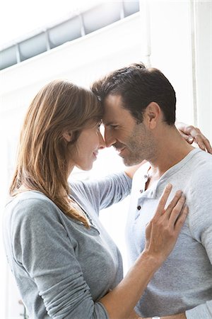 Couple touching noses and embracing by open window Stock Photo - Premium Royalty-Free, Code: 632-07674656