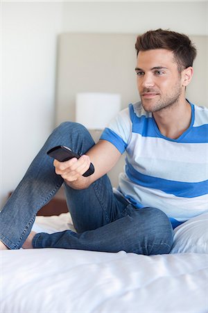 Young man reclining on bed watching tv Stock Photo - Premium Royalty-Free, Code: 632-07674776