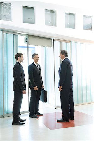 Businessmen chatting in building lobby Photographie de stock - Premium Libres de Droits, Code: 632-07809316