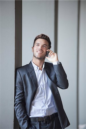 Young man leaning against buiding column talking on cell phone Stock Photo - Premium Royalty-Free, Code: 632-07809444