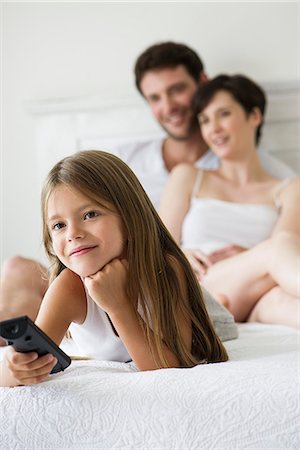 Little girl watching tv in bedroom with parents Stock Photo - Premium Royalty-Free, Code: 632-07809562