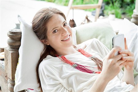 Young woman lying on back with smartphone in hands, portrait Stock Photo - Premium Royalty-Free, Code: 632-08001835