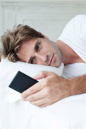 Man lying in bed using smartphone Foto de stock - Sin royalties Premium, Código: 632-08130031