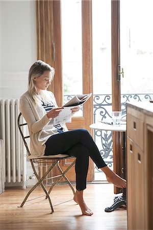 single woman sitting on a chair home - Young woman reading newspaper at home Stock Photo - Premium Royalty-Free, Code: 632-08227623