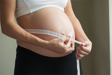 Pregnant woman measuring waistline Stock Photo - Premium Royalty-Free, Code: 632-08227763