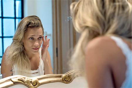 Woman looking bleary-eyed at self in bathroom mirror Fotografie stock - Premium Royalty-Free, Codice: 632-08331542