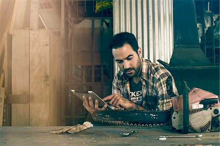 Man searching internet for chainsaw repair instructions Stock Photo - Premium Royalty-Free, Code: 632-08698328