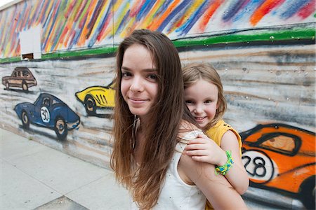 Teenage girl giving her little sister a piggyback ride, portrait Stock Photo - Premium Royalty-Free, Code: 632-08698479