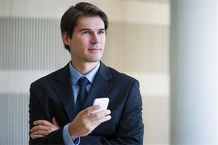 simsearch:6109-06685044,k - Businessman holding smartphone, looking away in thought Stock Photo - Premium Royalty-Free, Code: 632-08698470