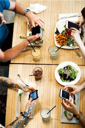 restaurant friends - Diners using smartphones in restaurant, cropped overhead view Stock Photo - Premium Royalty-Free, Code: 632-09039783