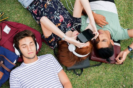 Friends lying on grass, using virtual reality simulator and listening to headphones Stock Photo - Premium Royalty-Free, Code: 632-09157968