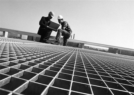 Two men wearing hard hats, looking at laptop computer, b&w Stock Photo - Premium Royalty-Free, Code: 632-01146826