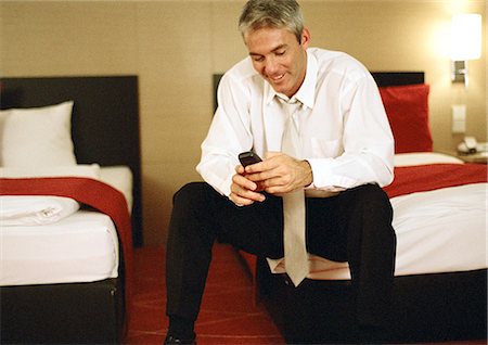 simsearch:400-06632132,k - Businessman sitting on bed, using cell phone Stock Photo - Premium Royalty-Free, Code: 632-01148068